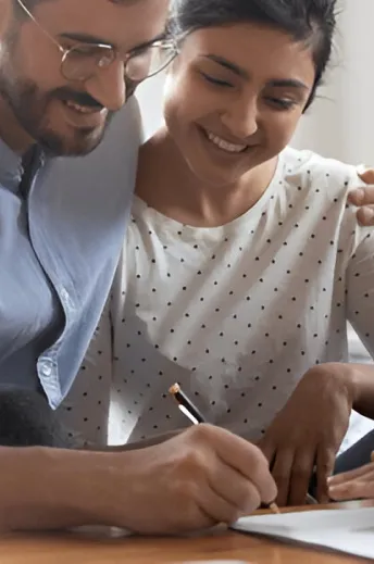 A happy couple reviewing documents together in a bright, well-lit indoor setting.