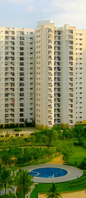 High-rise residential apartments with a green lawn and a swimming pool in the foreground.