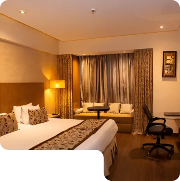 A luxurious hotel room featuring a king-sized bed, decorative pillows, and warm lighting.