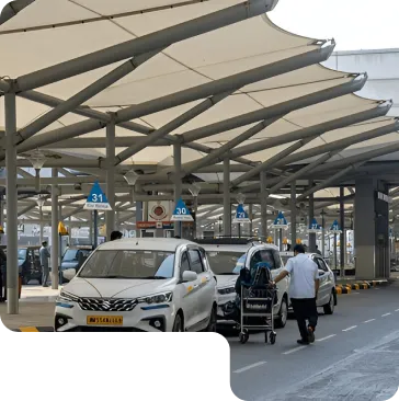 A sheltered car parking area with white cars and a modern steel structure.