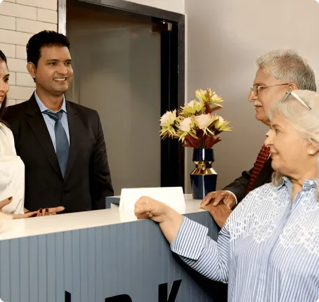  A receptionist handing over documents to an elderly couple at a hotel check-in counter.